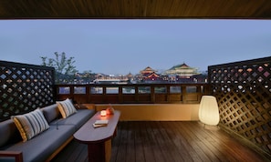 A balcony with a wooden floor, a sofa with cushions, a table with a candle, and a view of traditional buildings. - Blossom Hill Hotel Nanjing Lishui (Nanjing)