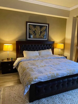 Cozy retreat with a tufted headboard bed, bedside tables, and a framed artwork.