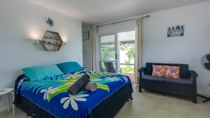 A bedroom with a bed, a sofa, a ceiling fan, and a balcony with curtains.