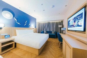 A hotel room with a bed, a desk, a TV, and a wall with a bird mural. - Crystal Orange Hotel Xinyi Center (Xuzhou)