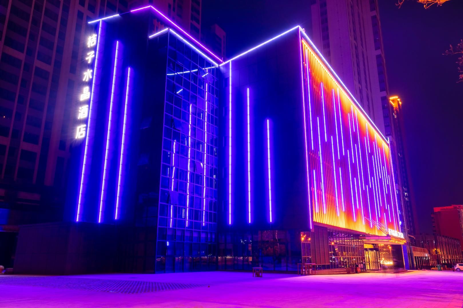 A modern building with a glass facade and illuminated vertical lines.