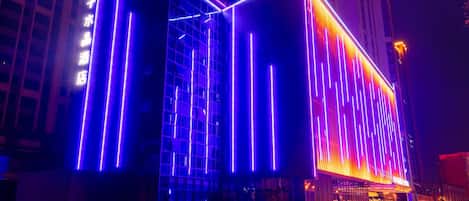 A modern building with a glass facade and illuminated vertical lines.