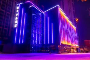 Un edificio moderno con fachada de vidrio y líneas verticales iluminadas.