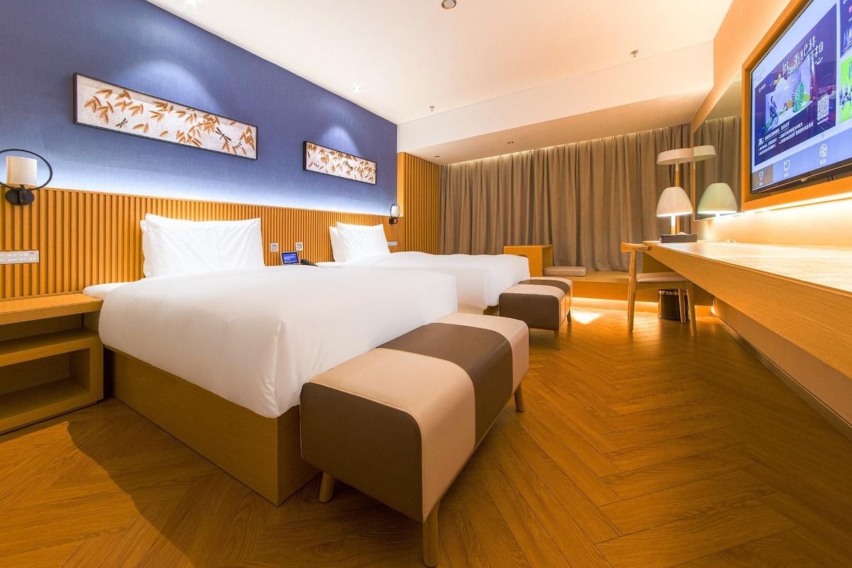 A hotel room with a large bed, bedside tables, a desk, and a television.