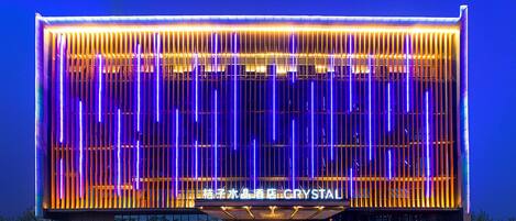 A modern building with a glass facade and vertical light strips.