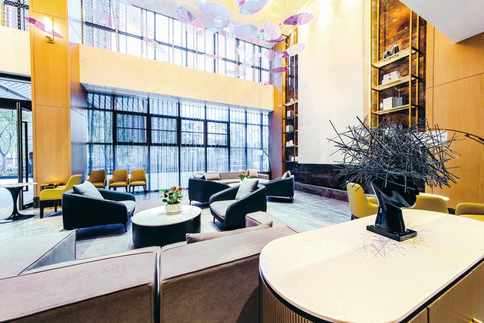 A spacious lobby with seating areas, a reception desk, and a large window providing a view of the outdoors.