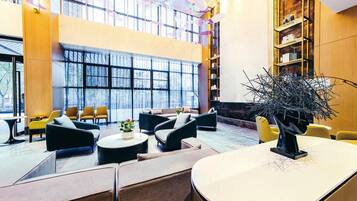 A spacious lobby with seating areas, a reception desk, and a large window providing a view of the outdoors.