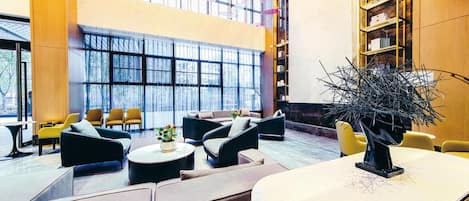 A spacious lobby with seating areas, a reception desk, and a large window providing a view of the outdoors.