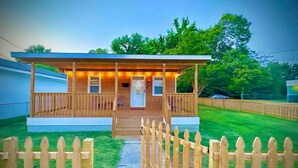 A wooden cabin with a porch, a door, and a small window. - Colonial Beach Cottage, 7 minutes walk to beach! (Colonial Beach)