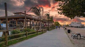 A waterfront promenade with wooden walkways, benches, and a restaurant with outdoor seating. - Colonial Beach Cottage, 7 minutes walk to beach! (Colonial Beach)
