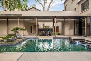 A modern outdoor pool area with a built-in waterfall feature, surrounded by a minimalist garden with rocks and small trees. - Blossom Hill Hotel Nanjing Laomendong Zhuqueli (Nanjing)