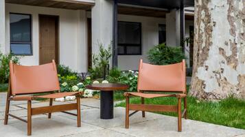Two leather chairs with metal frames and a small round table in a courtyard with a building in the background.