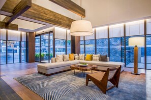 A modern living room with a sectional sofa, a coffee table, and a large window offering a view of the cityscape. - Blossom Hill Hotel Nanjing Laomendong Zhuqueli (Nanjing)