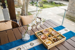 A wooden table with a glass vase of white flowers, a blue placemat, and a wooden tray with various food items. - Blossom Hill Hotel Nanjing Laomendong Zhuqueli (Nanjing)