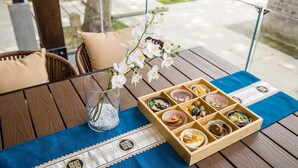 A wooden table with a blue placemat, a glass vase with white flowers, and a wooden tray with various food items. - Blossom Hill Hotel Nanjing Laomendong Zhuqueli (Nanjing)