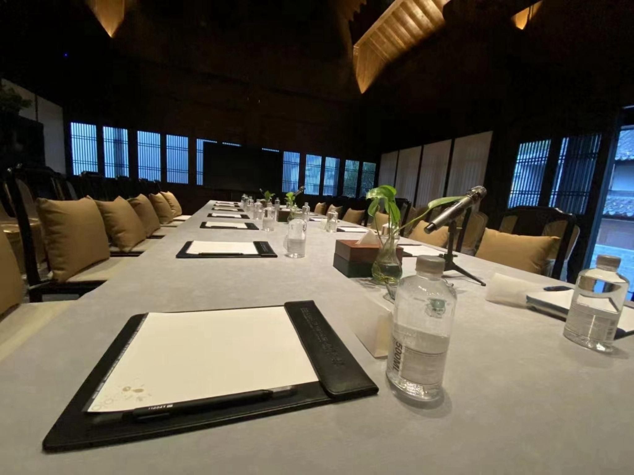 A conference room with a long table, chairs, and a projector screen.