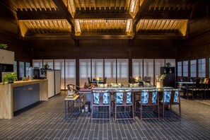 A spacious dining area with a high ceiling and wooden beams, featuring a long table with chairs and a bar area. - Blossom Hill Hotel Nanjing Laomendong Zhuqueli (Nanjing)