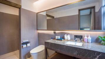 A modern bathroom with a marble sink, large mirror, and toiletries.