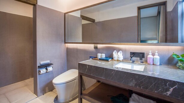 Un baño moderno con lavamanos de mármol, espejo grande y artículos de aseo.