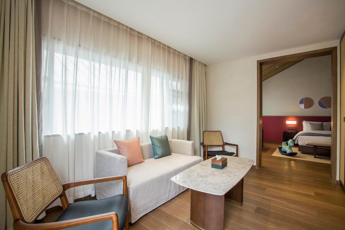 Quarto de hotel com sofá, cadeiras, mesa e cama.