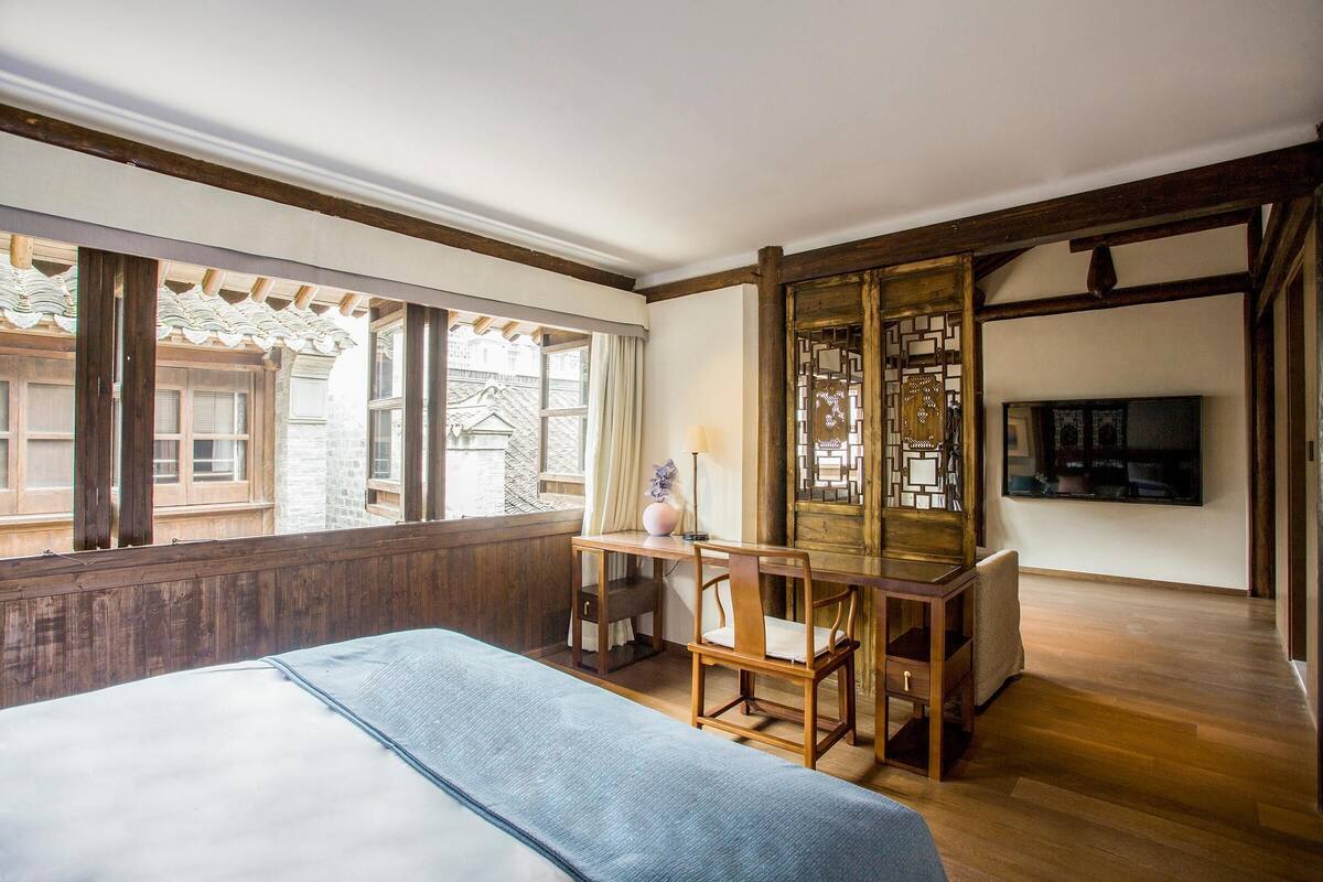 Quarto com cama, escrivaninha e televisão.