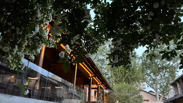 A modern building with a glass balcony, a stone pathway, and a small garden area. - Blossom Hill Hotel Nanjing Laomendong Zhuqueli (Nanjing)