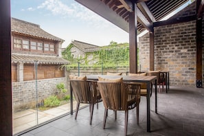 An outdoor patio with a table and chairs, a brick wall, and traditional buildings in the background. - Blossom Hill Hotel Nanjing Laomendong Zhuqueli (Nanjing)