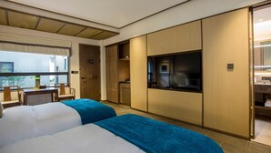 Una habitación de hotel con dos camas, televisión, escritorio y ventana con vistas.