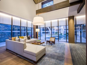 A modern hotel lobby with a large sofa, a coffee table, and a chair. There are large windows offering views of the outside. - Blossom Hill Hotel Nanjing Laomendong Zhuqueli (Nanjing)