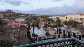Ett semesterparadis med en swimmingpool, palmer och utsikt över ett berg och en sjö.