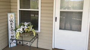 A house entrance with a 'WELCOME' sign, a glass door, and a flower arrangement on a metal table. - Newly remodeled offers many amenities with perfect location! (Ironton)