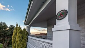 Ein weißes Gebäude mit einem Schild, auf dem „SERPENTINE ROSE“ steht, und Blick auf Bäume sowie eine entfernte Landschaft.
