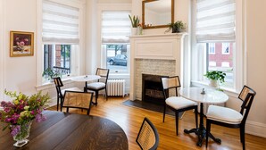 A room with a fireplace, two round tables, and four chairs.