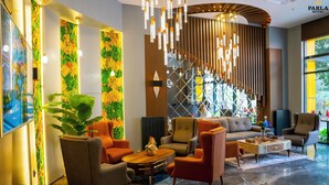 Un vestíbulo moderno con un conjunto de sofás, sillones naranjas, una mesa de centro y una planta grande.