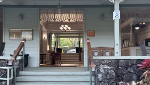A hotel entrance with a stone wall, wooden steps, a reception desk, and a sign advising to use handrails. - OCEAN Front Kona Studio - Spectacular view! (Kailua-Kona)