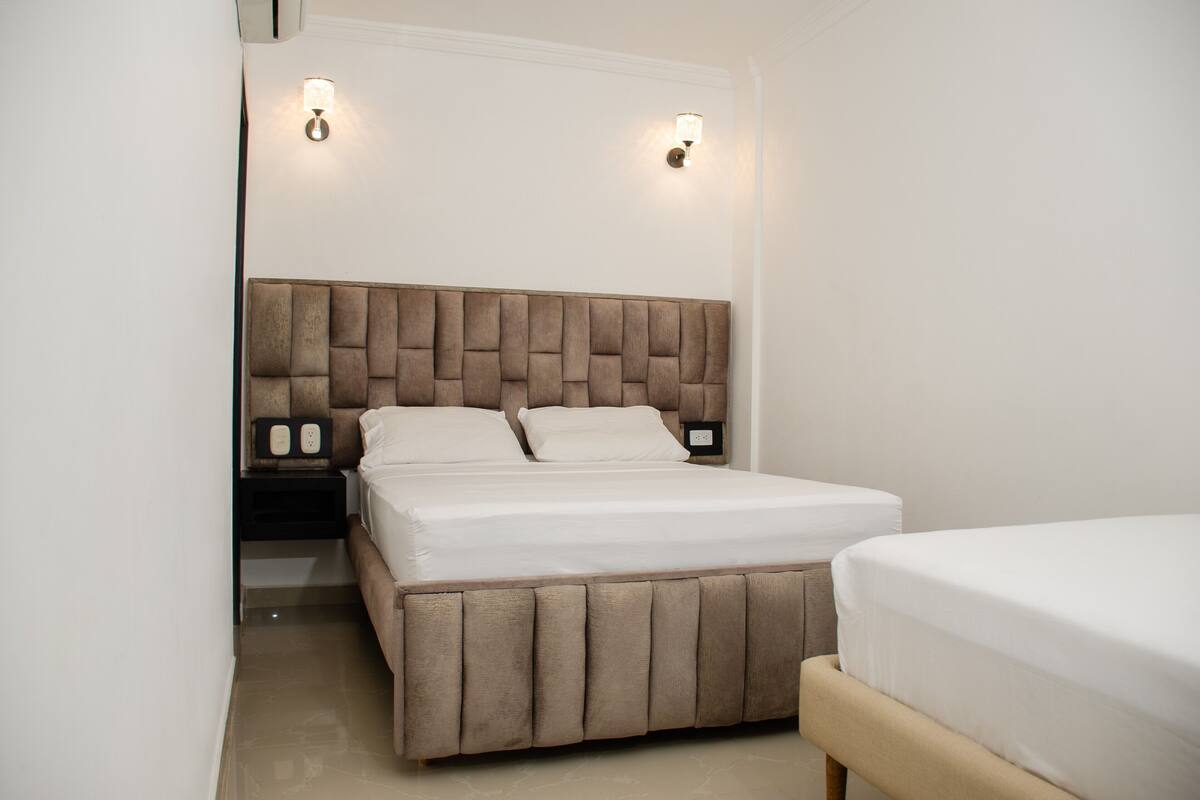 Une chambre à coucher avec un grand lit, une table de chevet et deux lampes fixées au mur.