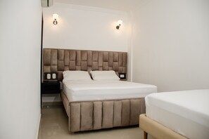 A bedroom with a large bed, a nightstand, and two wall-mounted light fixtures.