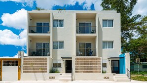 Un edificio de varios pisos con balcones, una entrada protegida por una reja y una escalera que conduce a la entrada.