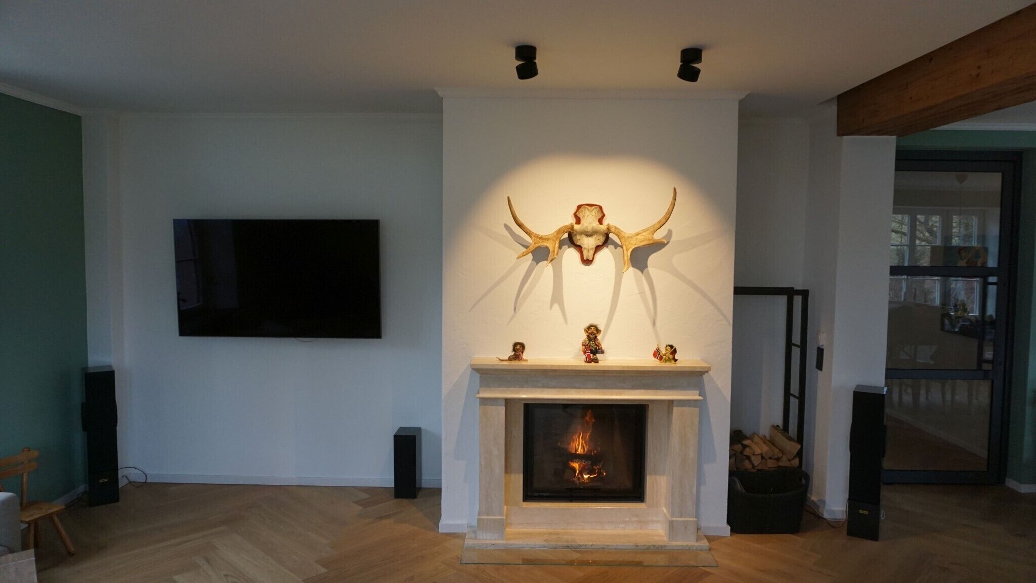 A modern living room with a fireplace, a mounted TV, and a large wall-mounted sculpture.