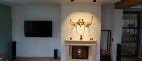 A modern living room with a fireplace, a mounted TV, and a large wall-mounted sculpture.