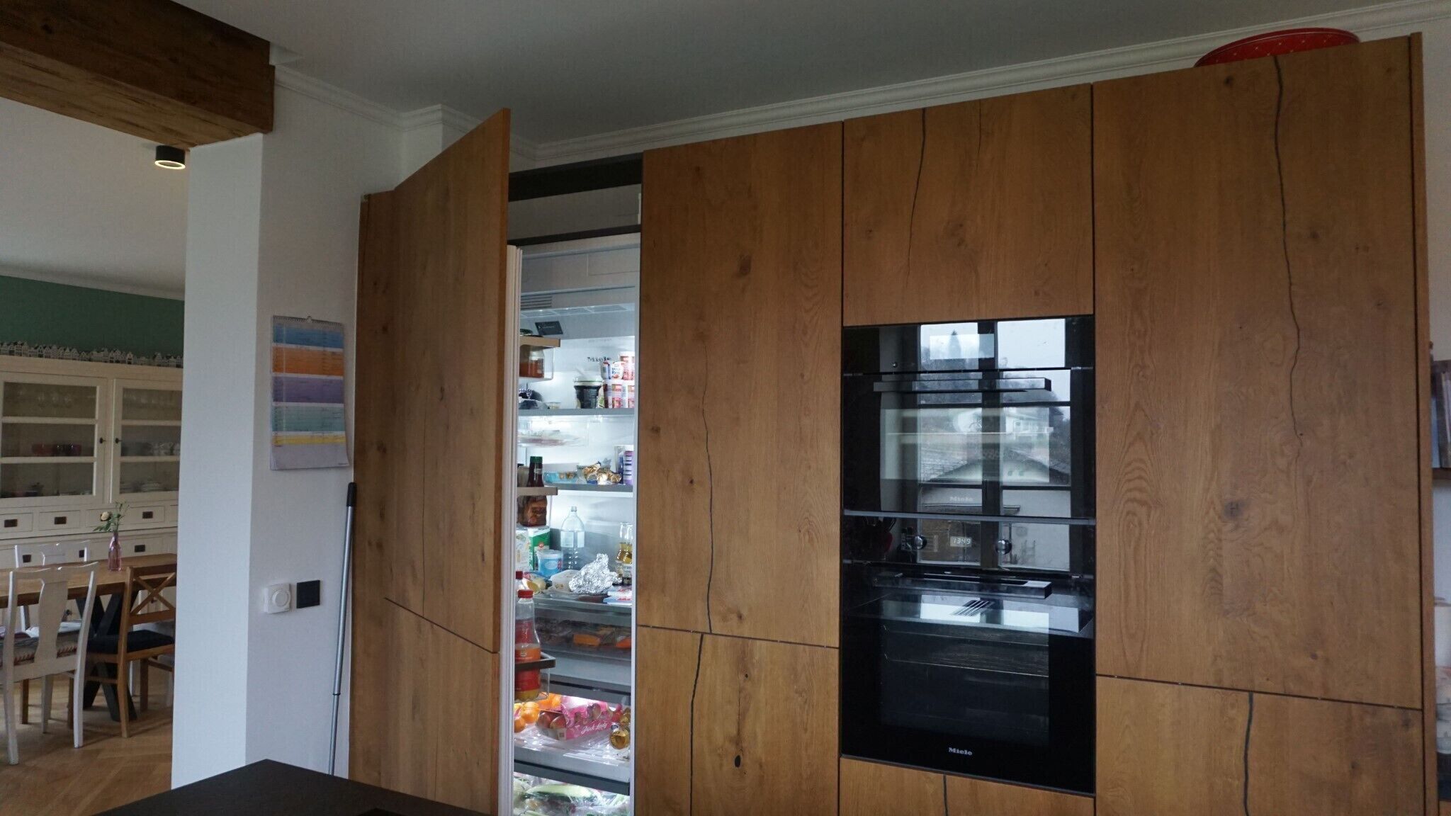 A kitchen with wooden cabinets, a built-in microwave, and a refrigerator.
