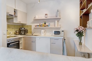 Una cocina compacta con estufa, microondas y pileta.
