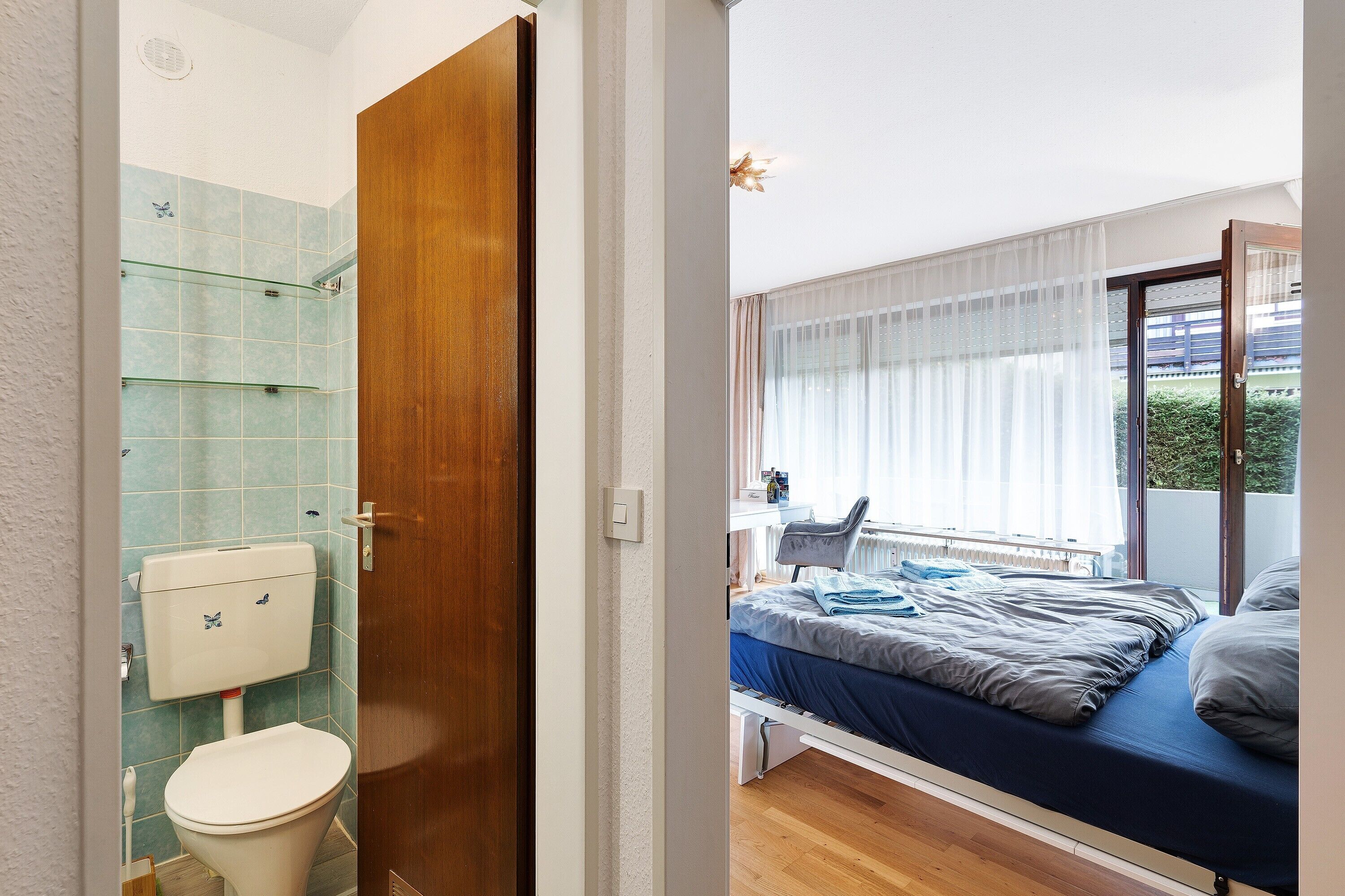 A bathroom with a toilet, shower, and glass shelves.