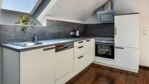 A compact kitchen with a skylight, built-in oven, and white cabinetry.