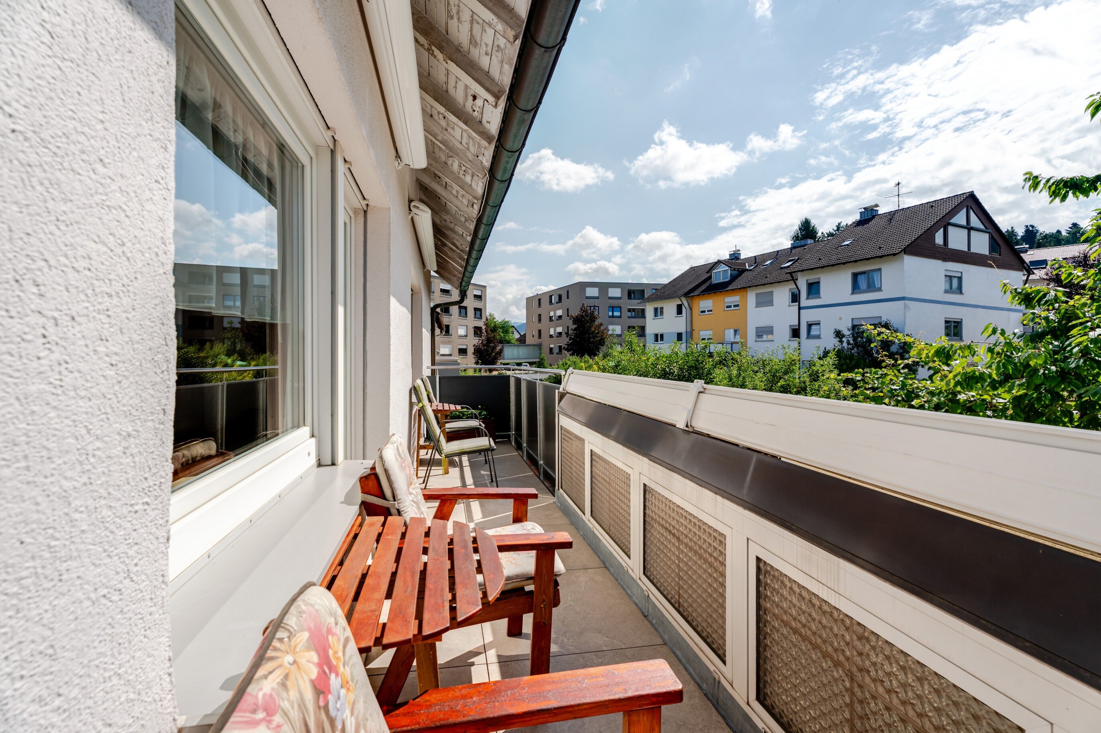 Ein Balkon mit Holzbänken und Blick auf benachbarte Gebäude.
