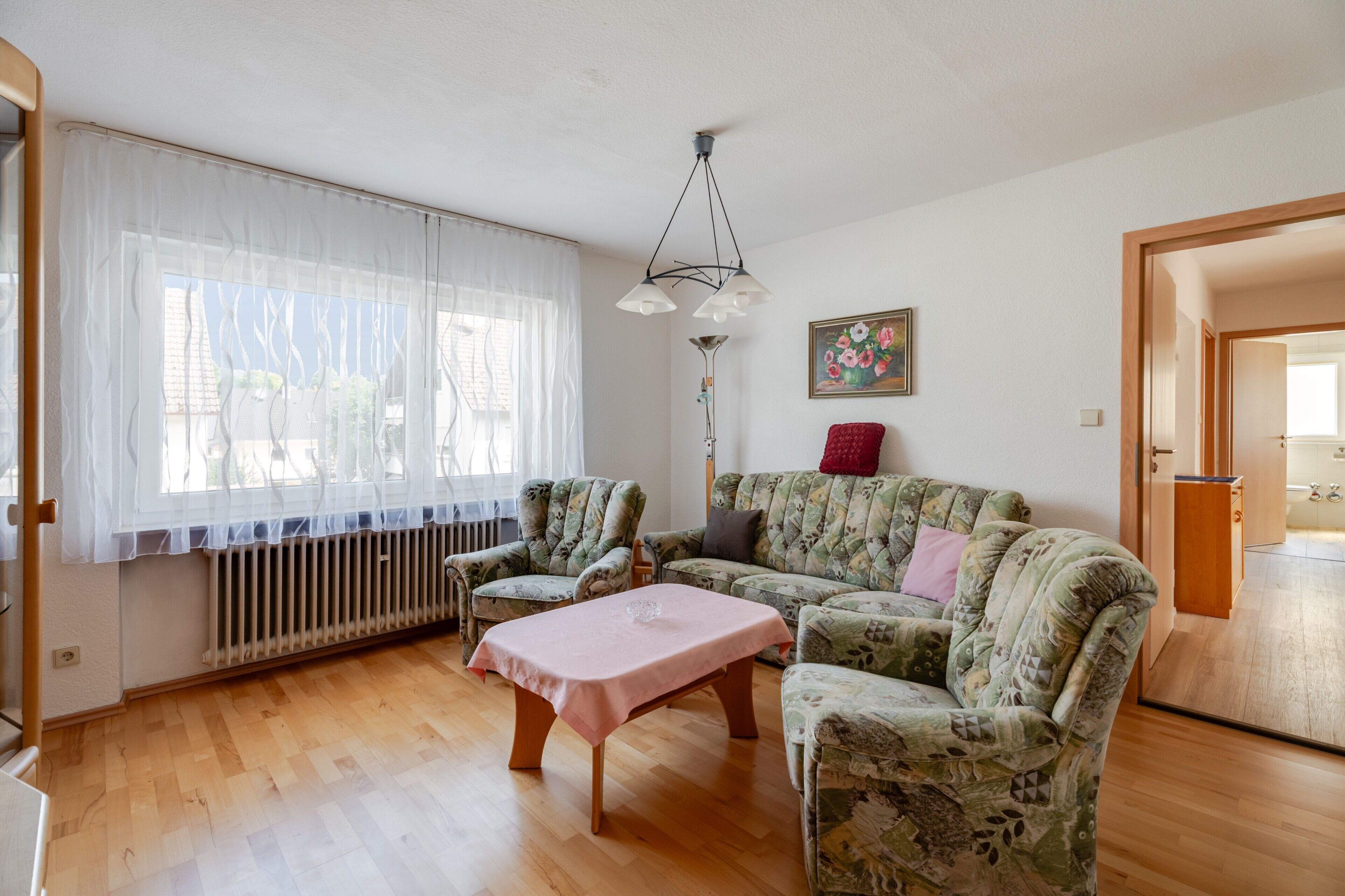 Ein Wohnzimmer mit einer Couch, Sesseln, einem Couchtisch und einer Heizung.