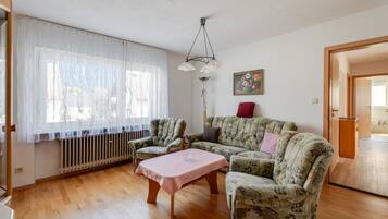 Ein Wohnzimmer mit einer Couch, Sesseln, einem Couchtisch und einer Heizung.