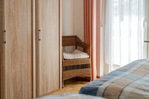 A bedroom with a wooden wardrobe, a wicker chair with a cushion, and a bed with a blue and white checkered bedspread. - Holiday Apartment 'Sonnenschein' with Mountain View, Balcony and Wi-Fi (Zell am Harmersbach)