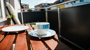A wooden table with a cup and saucer, a plate, and a spoon.