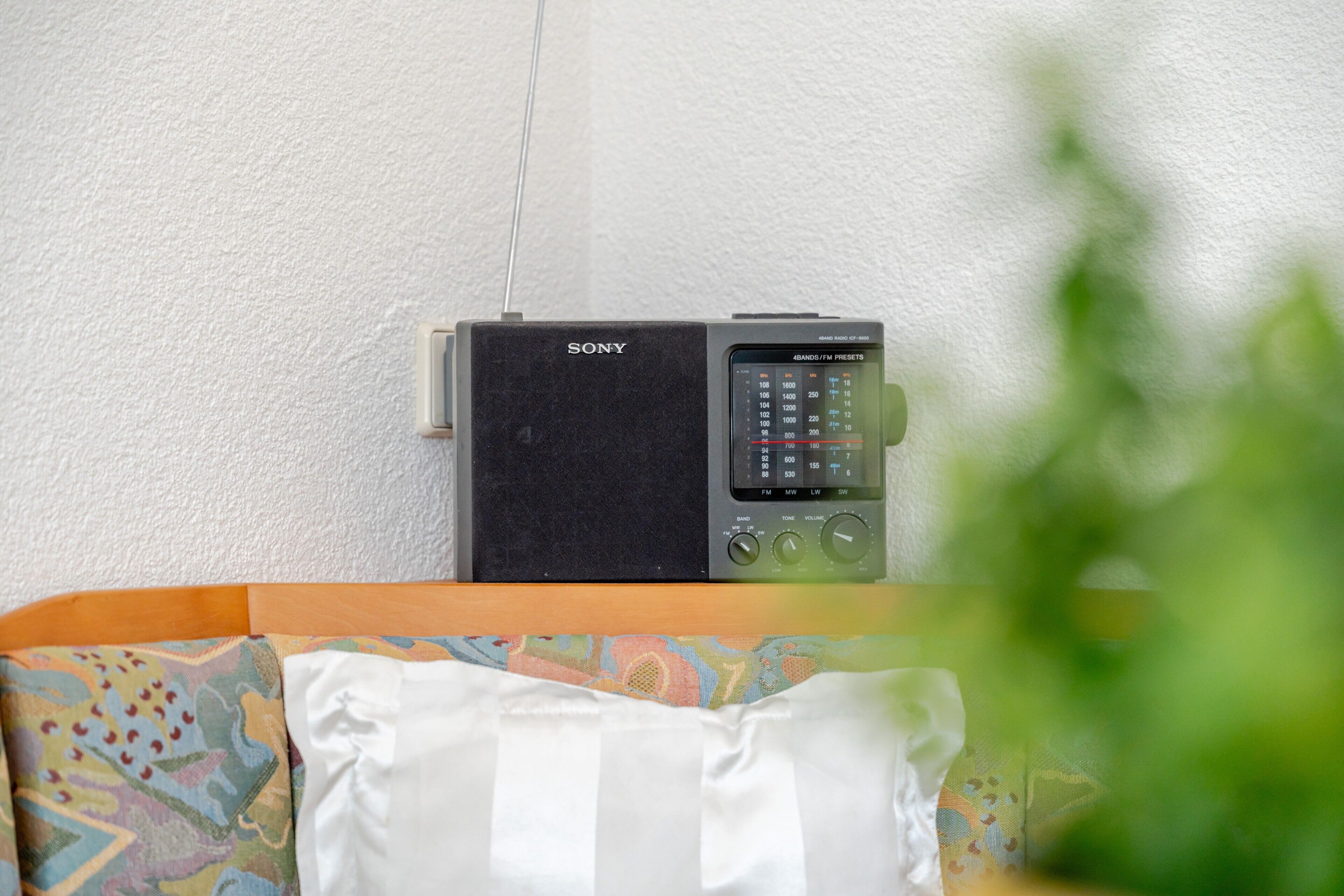A Sony radio with a display screen, placed on a wooden surface against a white wall.
